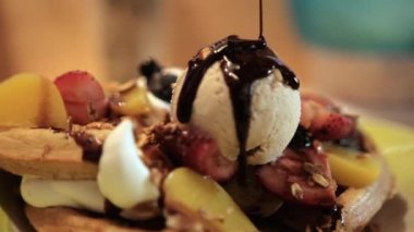 Dondurma kepçesini çikolata sosuyla kaplamak waffle 'ın üstünde meyve ile