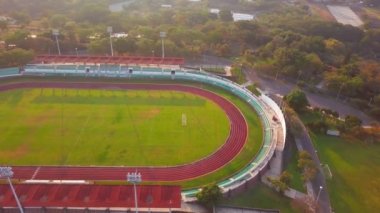 Ağaçlarla çevrili koşu pisti ve futbol sahasının havadan görüntüsü