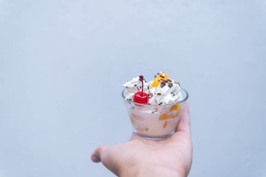 Elinde açık mavi arka planı olan bir fincan şeftali ve krema.