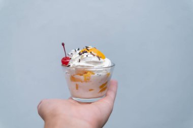 Elinde açık mavi arka planı olan bir fincan şeftali ve krema.