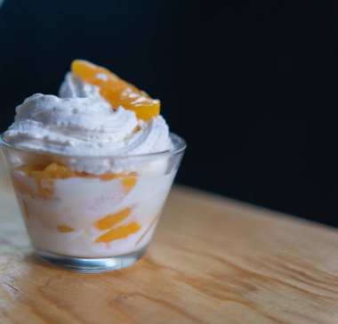 Ahşap zemin üzerinde bir fincan şeftali ve krema.