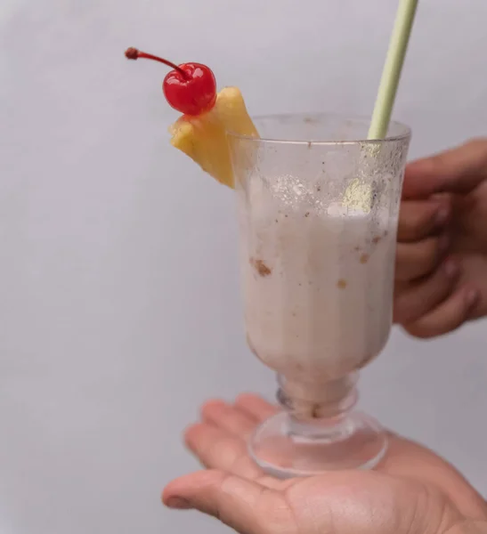 Mãos masculinas segurando saboroso milkshake baunilha com fundo cinza — Fotografia de Stock