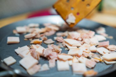 Tahta kaşık hindili jambonu yuvarlak ızgaranın üzerine taşıyor.