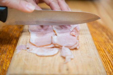 Kesme tahtasında taze hindi eti dilimleyen eller.