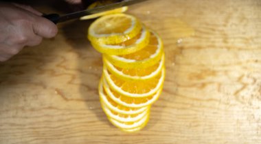 Odun kesme tahtasının üzerinde turuncu kesen ellerin üst görüntüsü