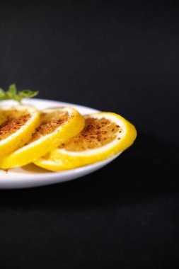 Siyah yüzeyde kırmızı biber tozlu portakal dilimleri.