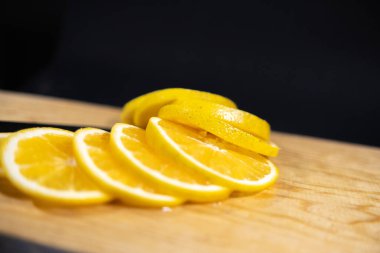 Ahşap yüzeyde taze portakal dilimleri, siyah arkaplan.