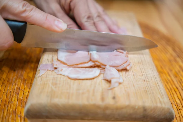 Mains coupant des tranches de jambon de dinde fraîche sur une planche à découper — Photo