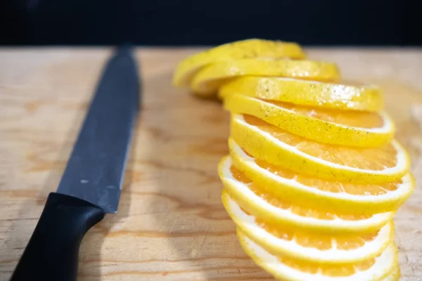 Orange slices and knife on wooden surface with black background — Stock Photo, Image