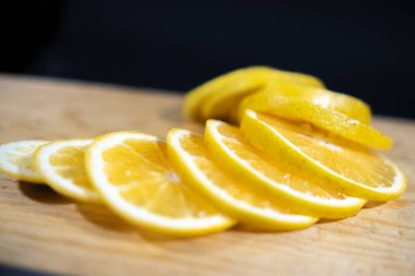 Ahşap yüzeyde taze portakal dilimleri, siyah arkaplan.