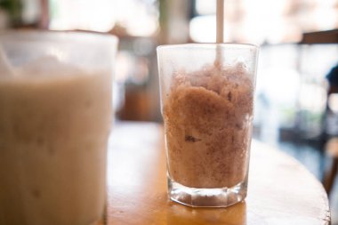 Lezzetli görünümlü frappuccino ve bulanık arkaplanlı bardak içinde milkshake.