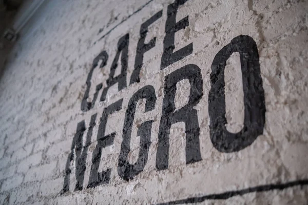 Café preto escrito em espanhol na parede de tijolo branco — Fotografia de Stock