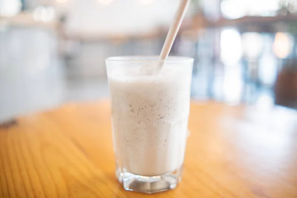 Milkshake com palha em vidro acima da mesa de madeira — Fotografia de Stock