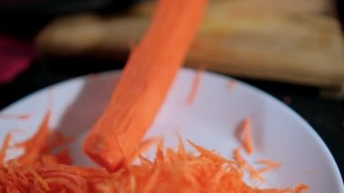 Eller ince havuç soyarken jülyen soyacağı beyaz tabağın üstünde.