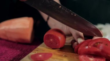 Tahta kesme tahtasıyla domates doğrayan eller.