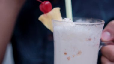 Adam elinde tutuyor ve samanla lezzetli vanilyalı milkshake içiyor.