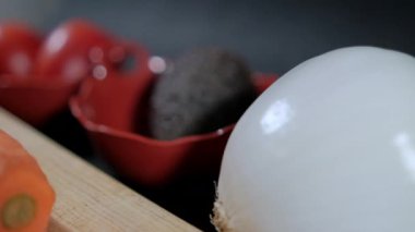 Kesme tahtasındaki soyulmuş havuçlar daha fazla sebzeyle çevrili.