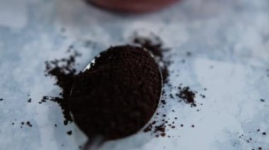 Beyaz mermer yüzeyde kaşık dolusu öğütülmüş kahve.