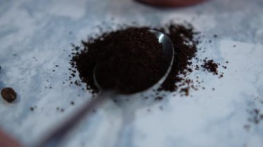 Beyaz mermer yüzeyde kaşık dolusu öğütülmüş kahve.