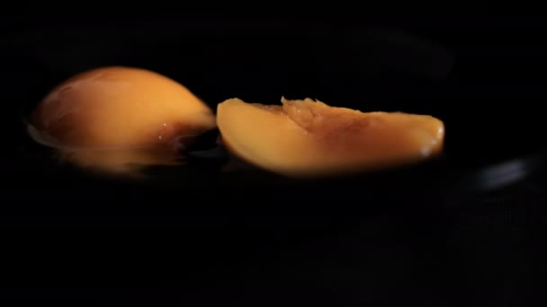 Meio pêssego descascado salpicando no fundo preto molhado — Vídeo de Stock