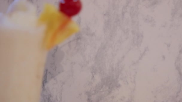 Milkshake de baunilha com frutas na borda e acima do fundo de mármore branco — Vídeo de Stock