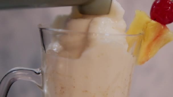 Wlewanie koktajlu waniliowego do szklanego kubka z owocami na krawędzi — Wideo stockowe