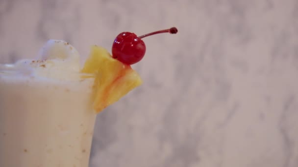 Ванильный молочный коктейль с фруктами на краю и на белом мраморном фоне — стоковое видео