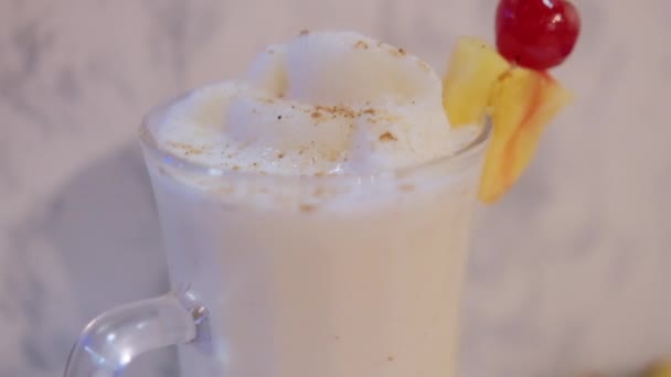 Vanilj milkshake med frukt på kanten och ovanför vit marmor bakgrund — Stockvideo