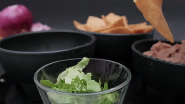 Cuencos de chips de tortilla, frijoles refritos y lechuga con fondo negro — Vídeos de Stock