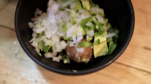 Подрібнену цибулю і перець чилі заливають у миску з гуакамоле — стокове відео