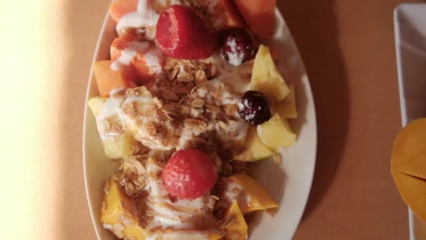 Teller mit geschnittenen Früchten mit Sahne und Haferflocken darauf — Stockvideo