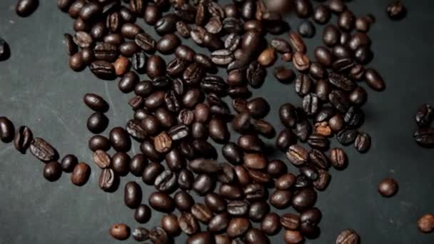 Hromada pražených kávových zrn se nalévá na černý povrch — Stock video