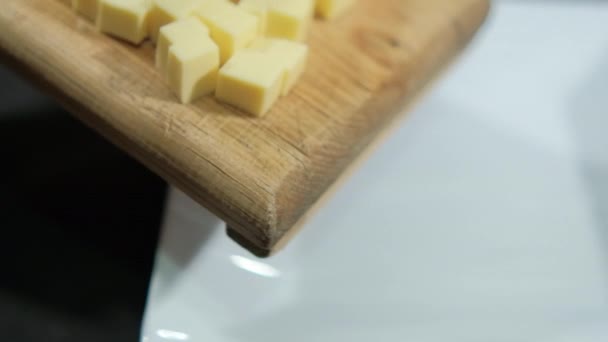 Coltello lentamente spazzando il formaggio tagliato a dadini da un tagliere — Video Stock
