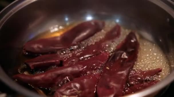 Pimientos rojos secos hirviendo en aceite dentro de la olla — Vídeos de Stock
