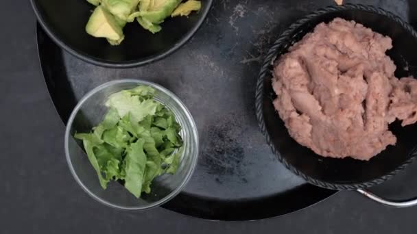 Bowls of tortilla chips, refried beans, and chopped avocado on Mexican comal — Stock Video