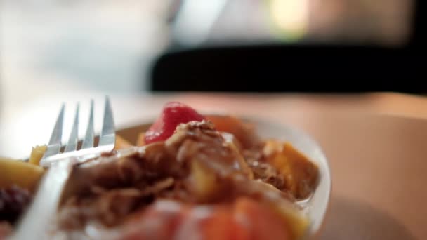 Placa de fruta en rodajas con crema, avena y tenedor encima — Vídeo de stock