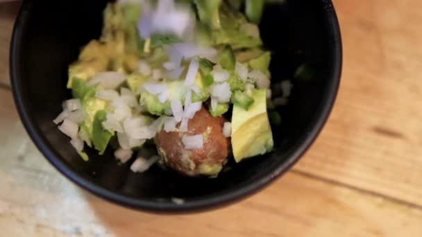 Подрібнену цибулю і перець чилі заливають у миску з гуакамоле — стокове відео