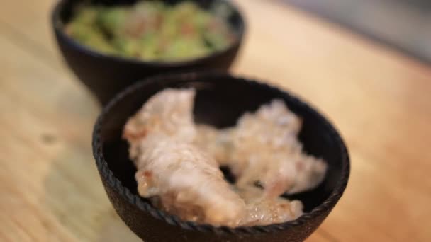 Bowls of pork rinds and guacamole on wooden surface — Stock Video