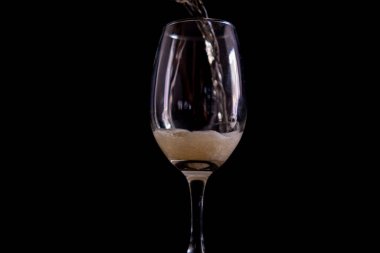 Siyah arkaplanlı cam bir kadehe bira dökmek.