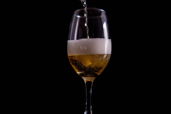 Despejar cerveja em uma taça de vidro com fundo preto — Fotografia de Stock