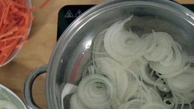 Bir tabak dilimlenmiş havucun yanında pişirme kabında soğan dilimleri.