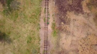 Çamur ve çimlerle çevrili eski tren raylarının üst görüntüsü