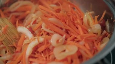 Tahta kaşık yer elması, havuç, domates ve soğan dilimleri karıştırılır.