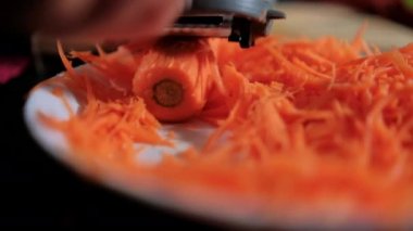 Eller ince havuç soyarken jülyen soyacağı beyaz tabağın üstünde.