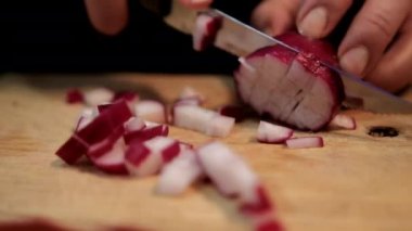 Kesme tahtasında taze turp doğrayan eller.