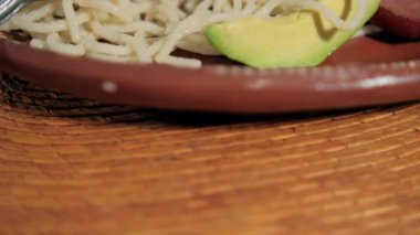 Geleneksel kil tabağın üzerinde beyaz spagetti ve avokado dilimleri var.