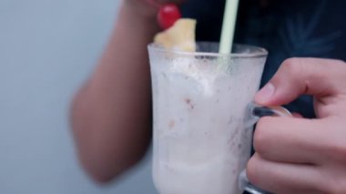 Adam elinde tutuyor ve samanla lezzetli vanilyalı milkshake içiyor.