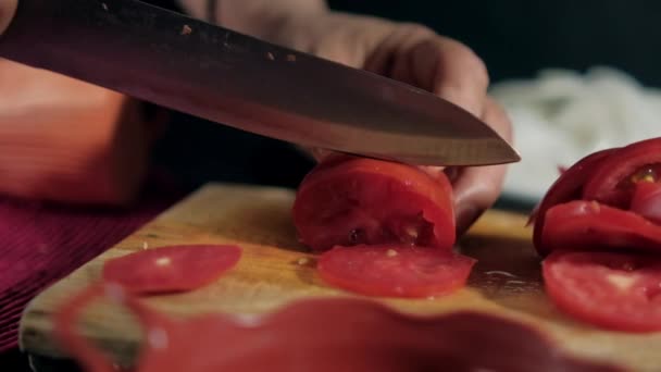 Handen snijden tomaat op een houten snijplank — Stockvideo