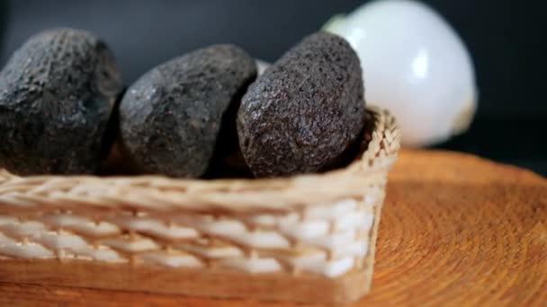 Drie avocado 's in traditionele palmmand met wazige zwarte achtergrond — Stockvideo