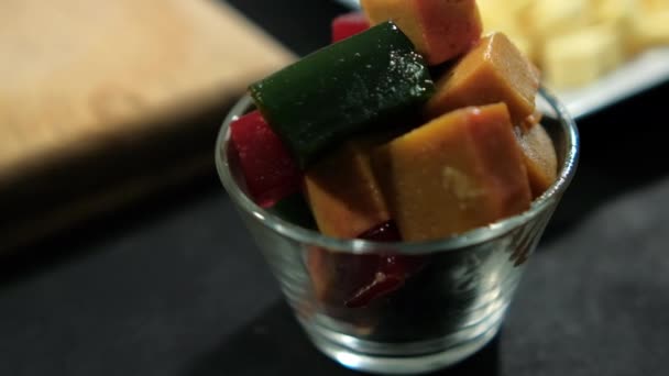 Copa de cubos de pasta de fruta fresca en la superficie negra — Vídeo de stock